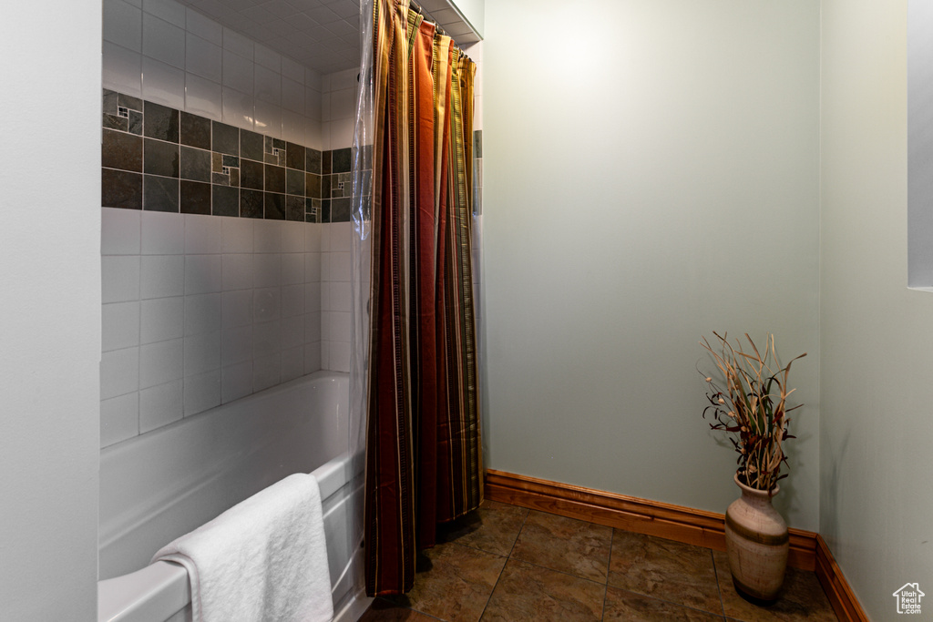 Full bathroom featuring shower / tub combo, baseboards, and stone finish flooring