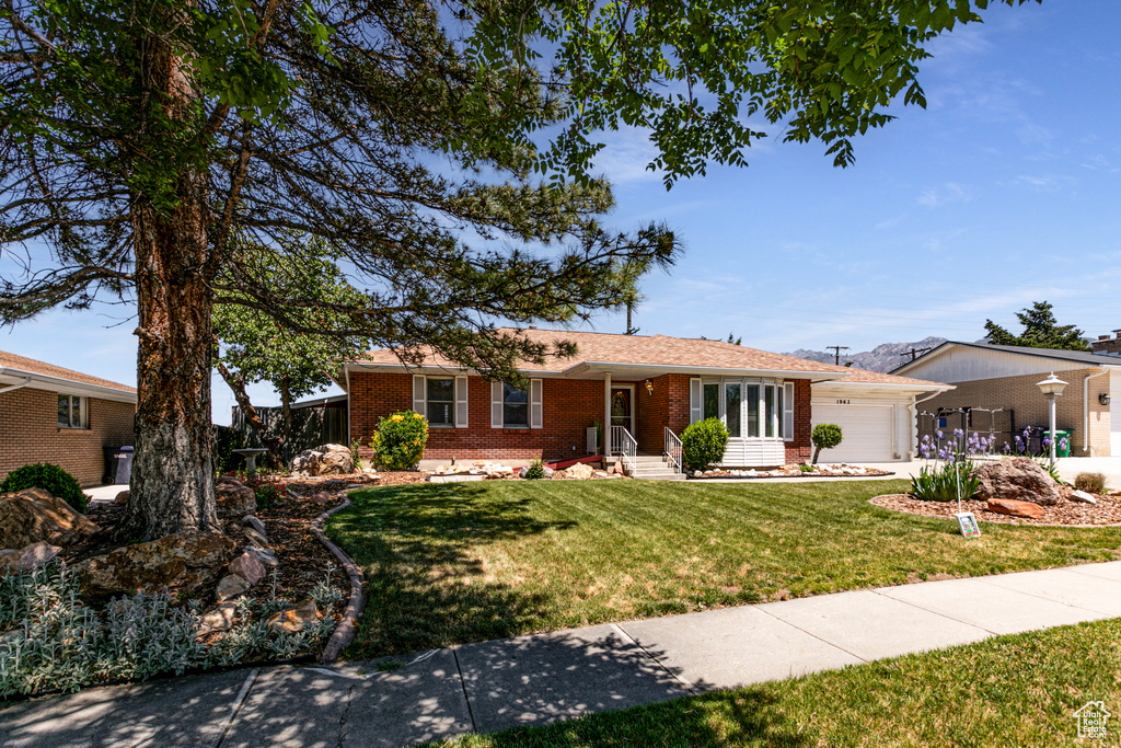 Ranch-style house with brick siding, an attached garage, a front yard, and concrete driveway