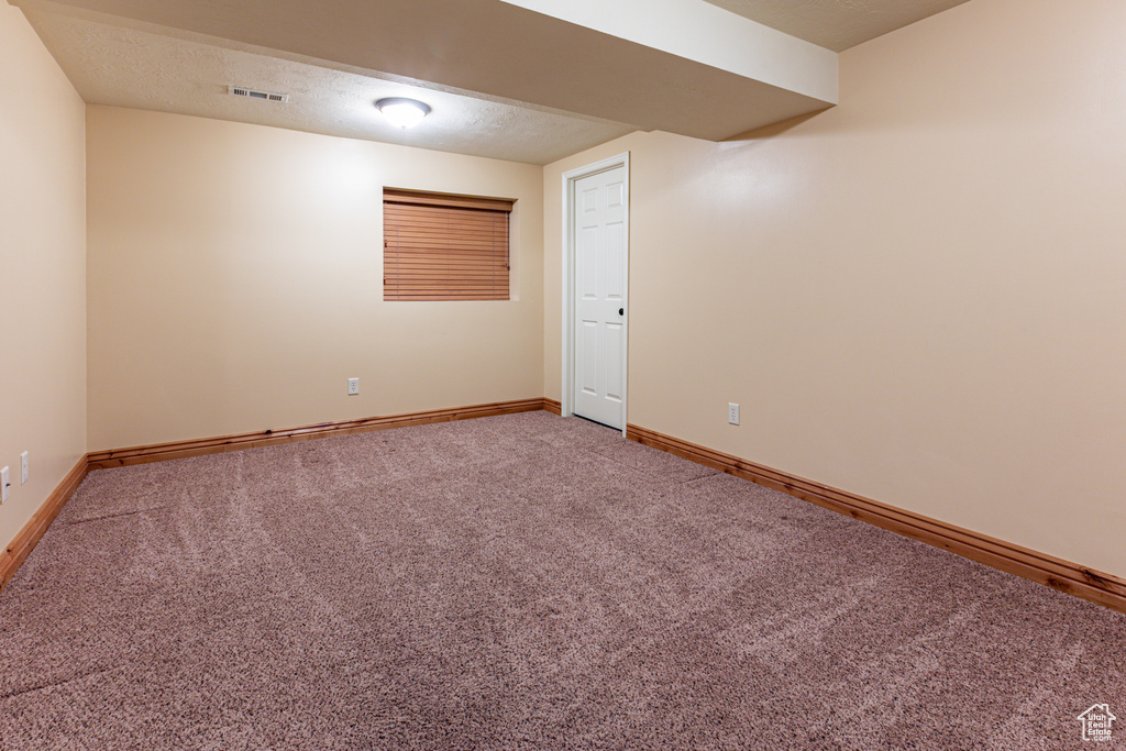 Unfurnished room with a textured ceiling, carpet, visible vents, and baseboards