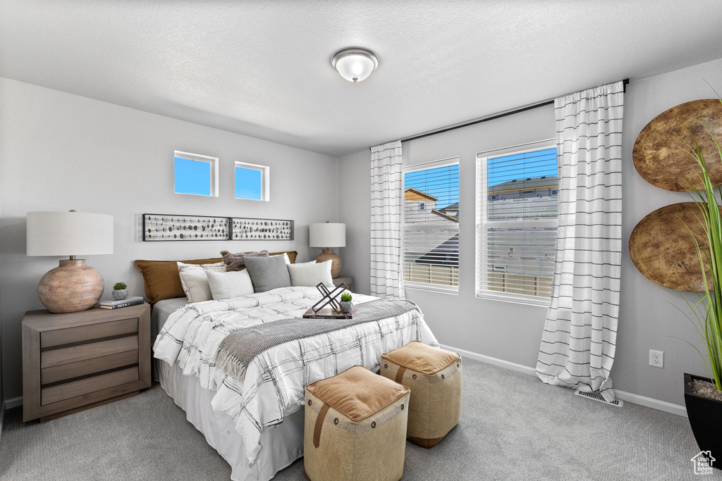 Carpeted bedroom featuring baseboards and a textured ceiling