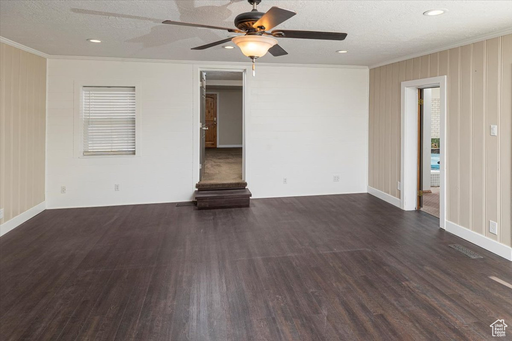 Spare room featuring dark wood-style floors, a textured ceiling, and crown molding