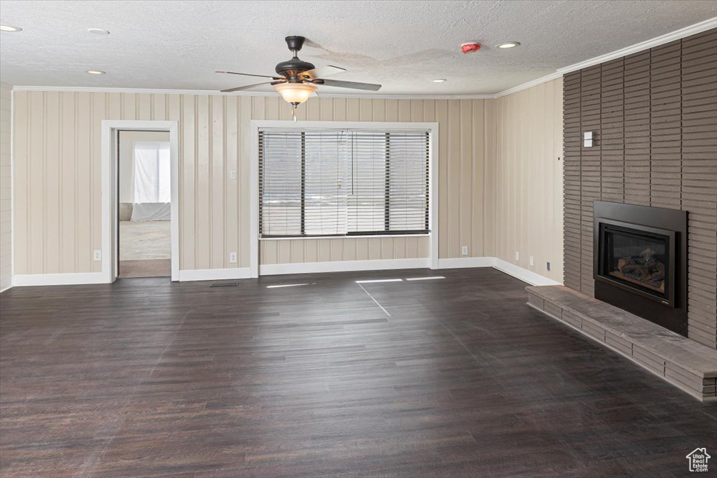 Unfurnished living room with ornamental molding, a brick fireplace, baseboards, and wood finished floors