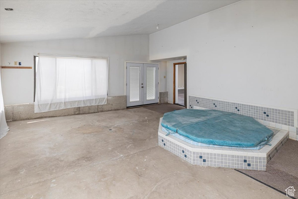 Unfurnished bedroom with lofted ceiling, french doors, and concrete floors