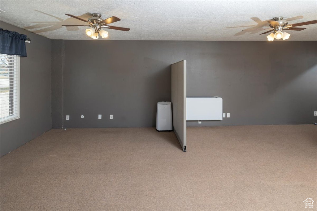 Carpeted empty room featuring ceiling fan and a textured ceiling