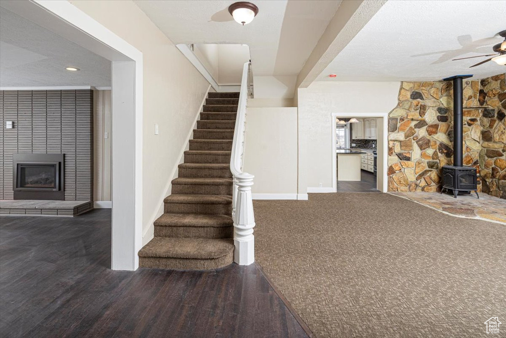 Staircase featuring a wood stove, ceiling fan, baseboards, and wood finished floors