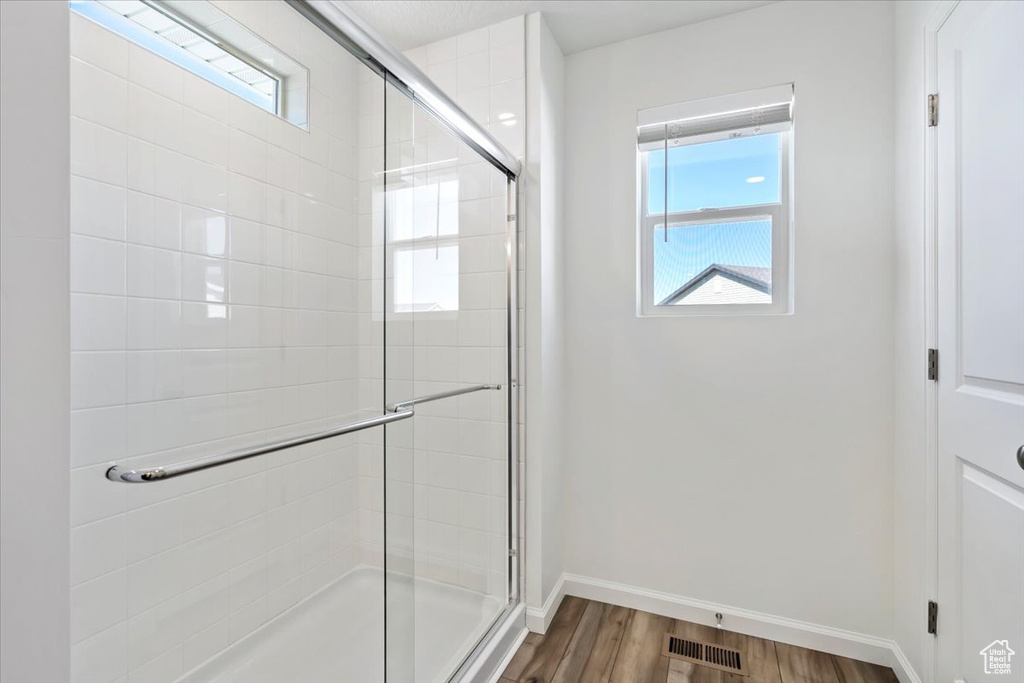 Bathroom with a stall shower, baseboards, visible vents, and wood finished floors