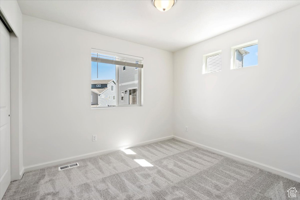 Unfurnished bedroom featuring multiple windows, carpet, visible vents, and baseboards