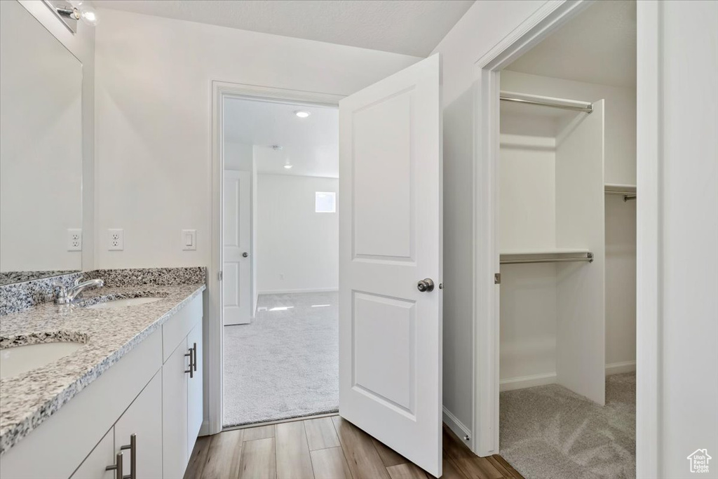 Bathroom featuring double vanity, wood finished floors, a sink, and baseboards