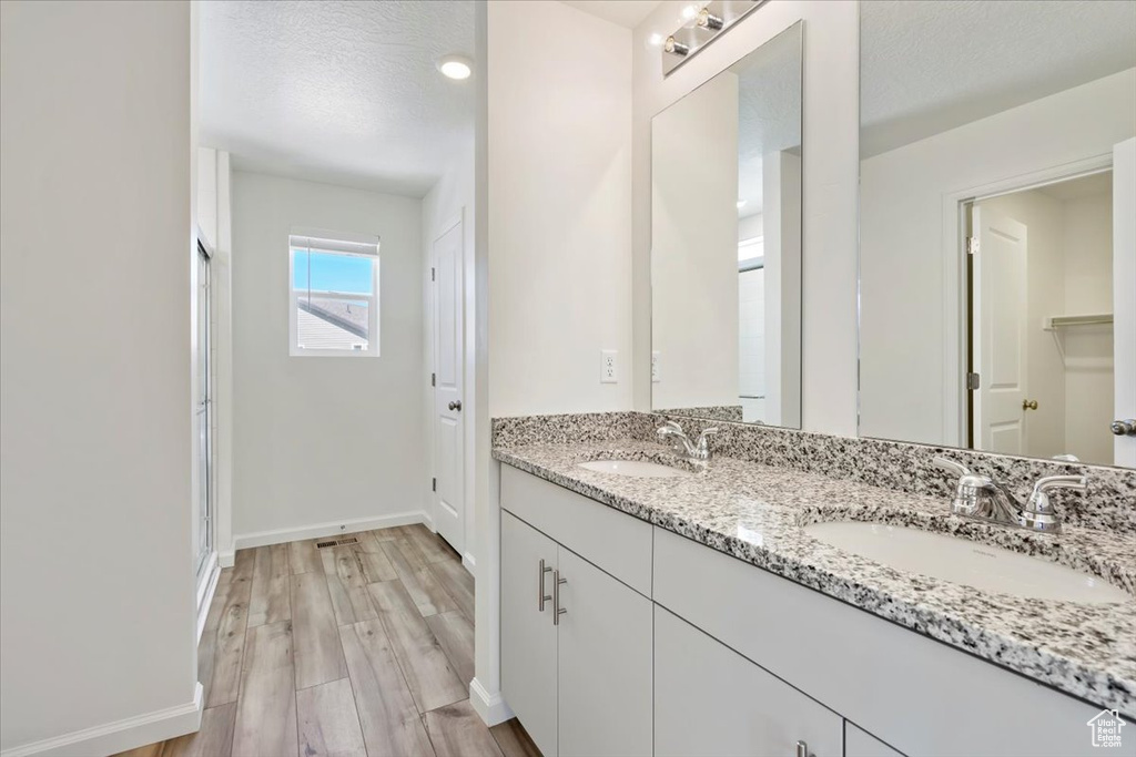 Bathroom with a sink, a textured ceiling, baseboards, and wood finished floors