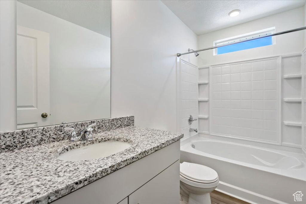 Bathroom with toilet, shower / washtub combination, wood finished floors, and vanity