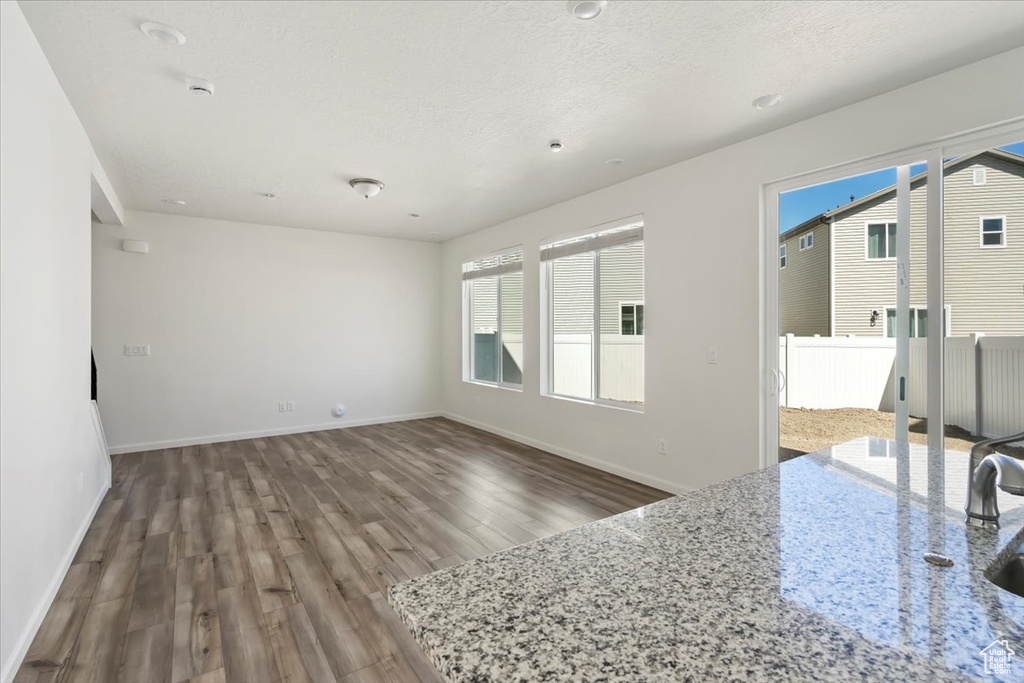 Unfurnished living room with a textured ceiling, baseboards, and wood finished floors