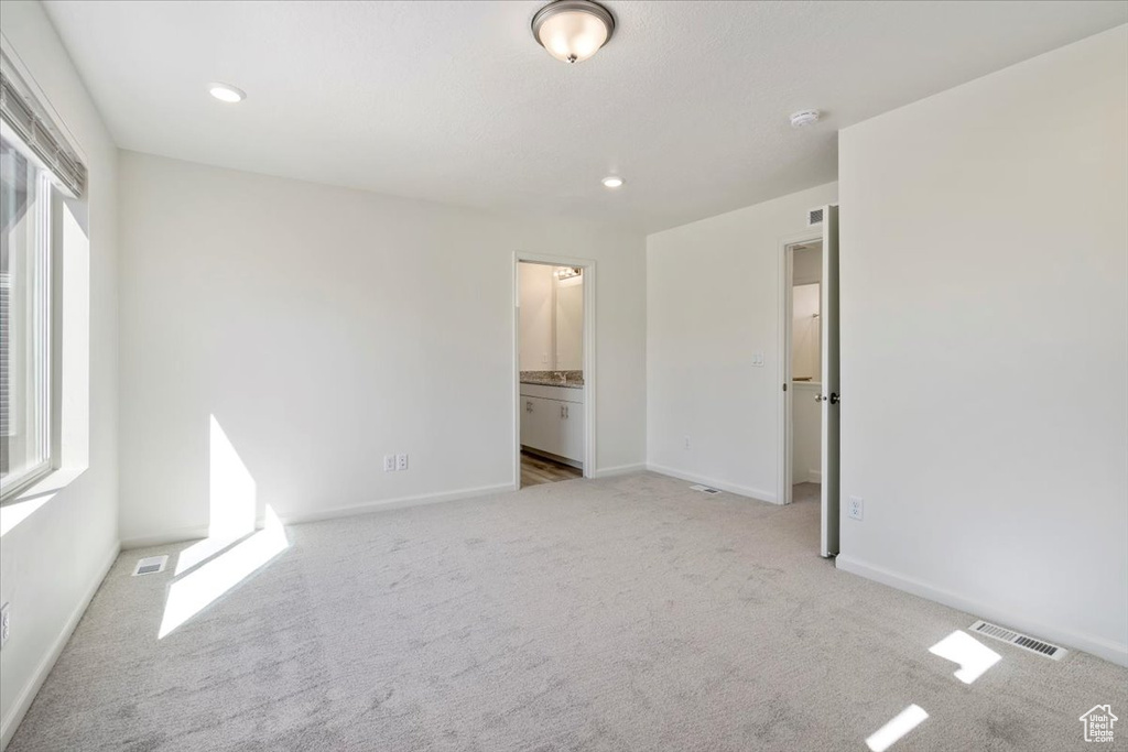 Unfurnished bedroom with baseboards, visible vents, ensuite bathroom, carpet flooring, and recessed lighting
