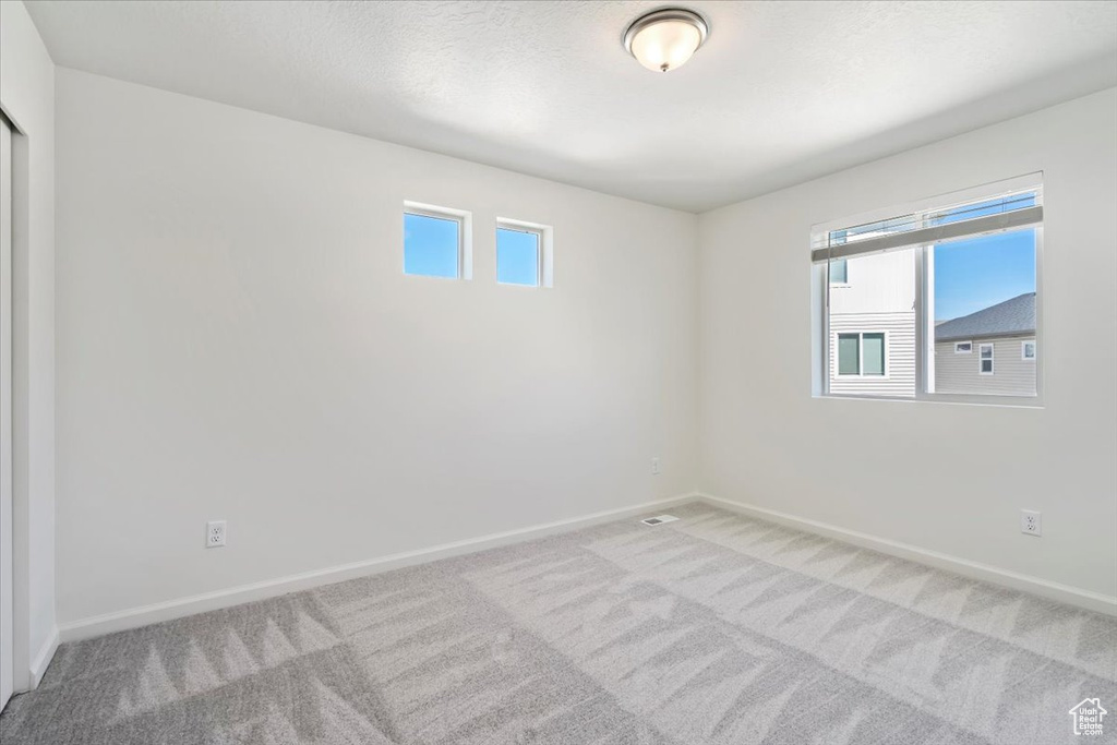 Unfurnished room featuring a textured ceiling, carpet floors, and baseboards