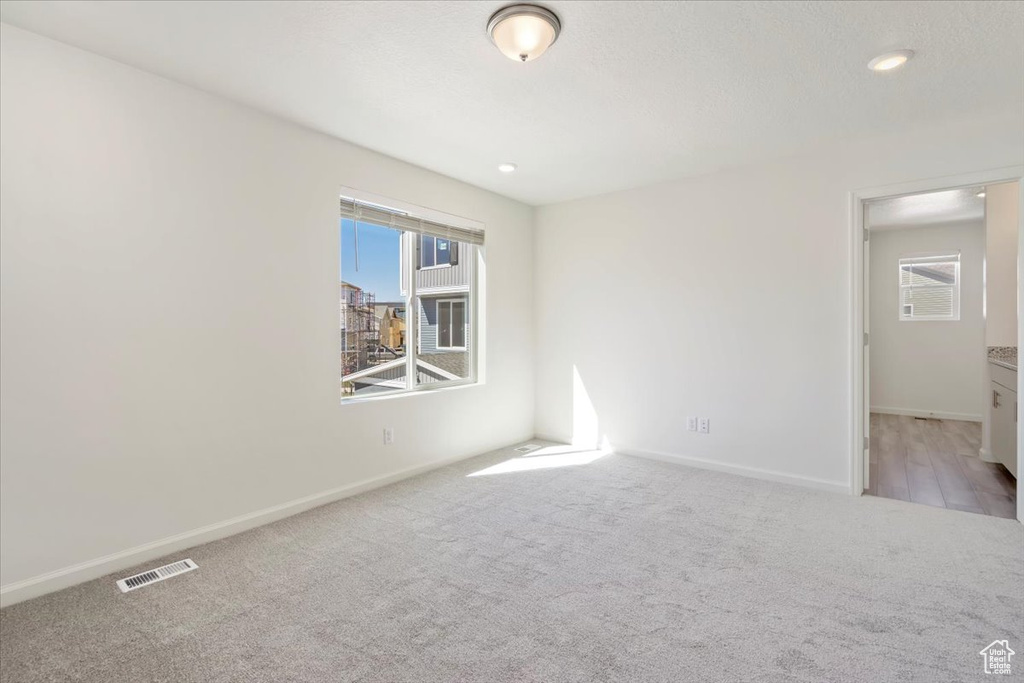 Unfurnished room with carpet floors, a healthy amount of sunlight, visible vents, and baseboards