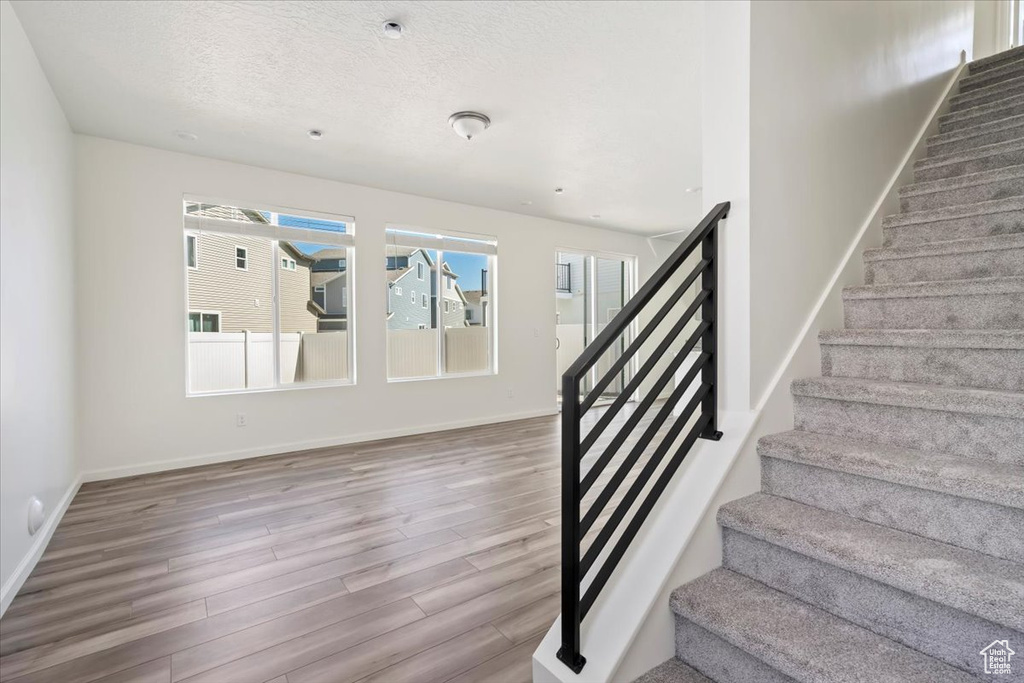Stairway featuring a textured ceiling, baseboards, and wood finished floors