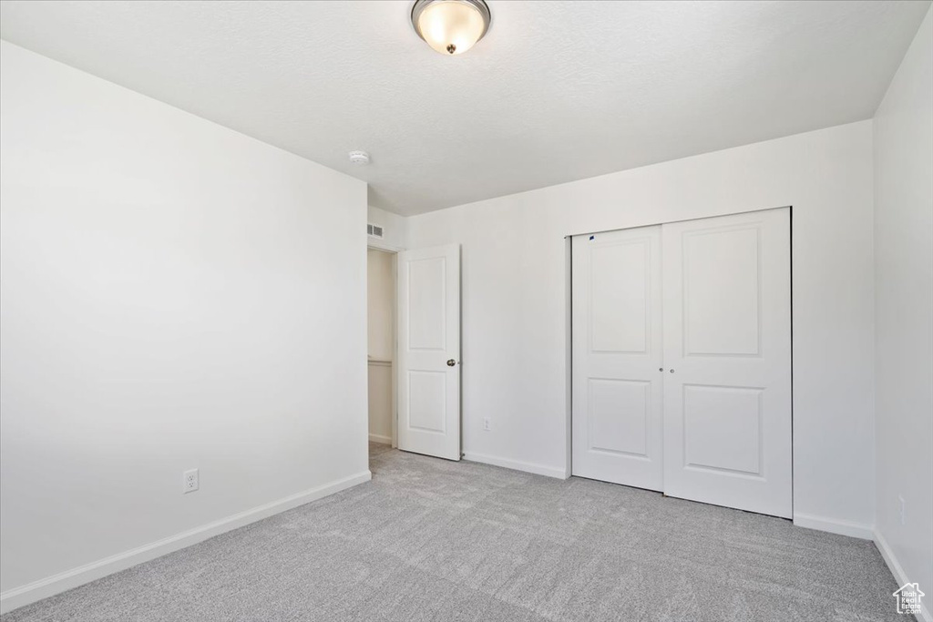 Unfurnished bedroom featuring carpet, a closet, a textured ceiling, and baseboards
