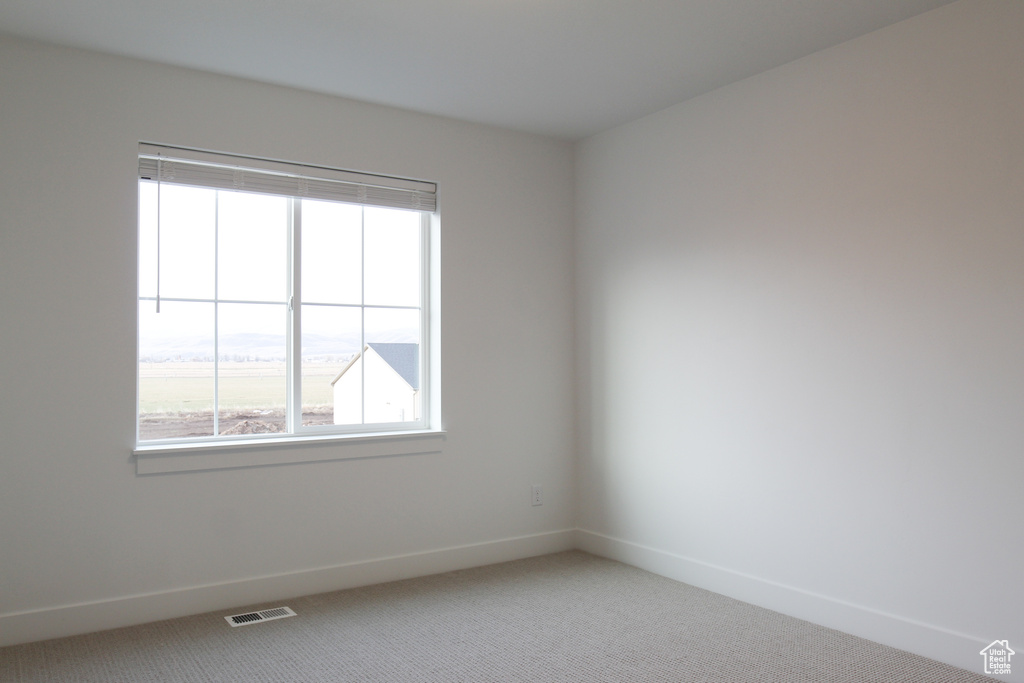 Unfurnished room featuring light carpet and baseboards