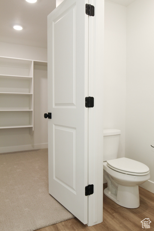 Bathroom featuring toilet, baseboards, and wood finished floors