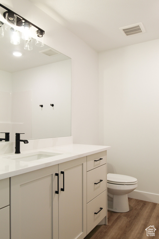 Bathroom featuring wood finished floors, toilet, and vanity