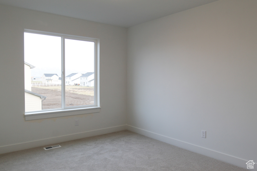 Spare room with healthy amount of natural light, light colored carpet, and baseboards