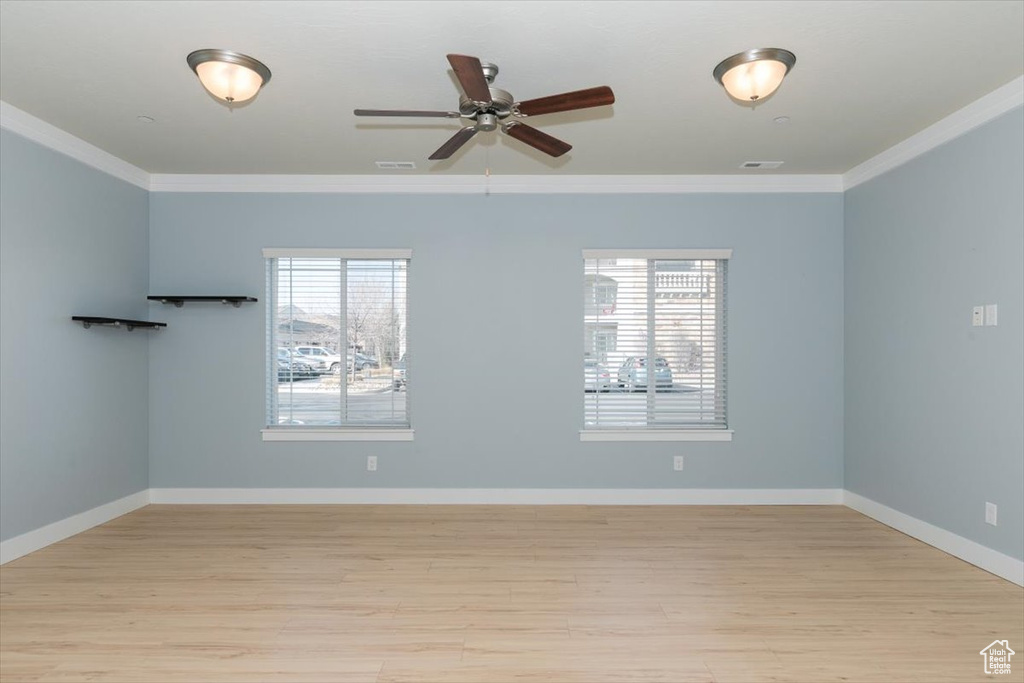 Unfurnished room featuring light wood-style flooring, baseboards, visible vents, and ornamental molding