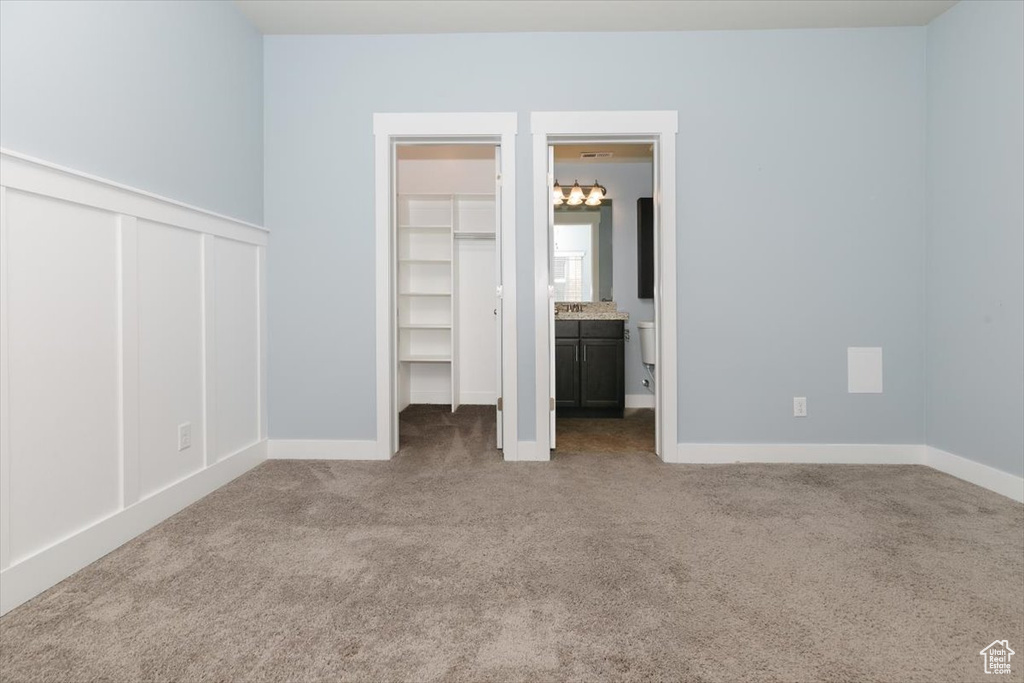 Unfurnished bedroom with a closet, ensuite bath, and carpet