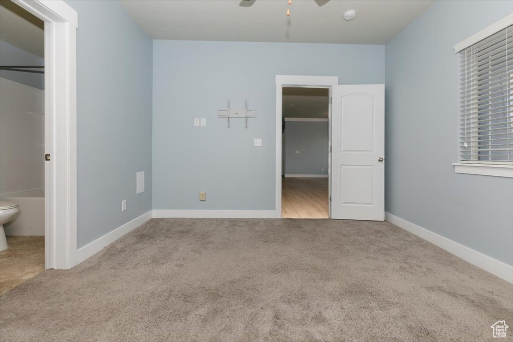 Unfurnished bedroom featuring a walk in closet, baseboards, and carpet floors