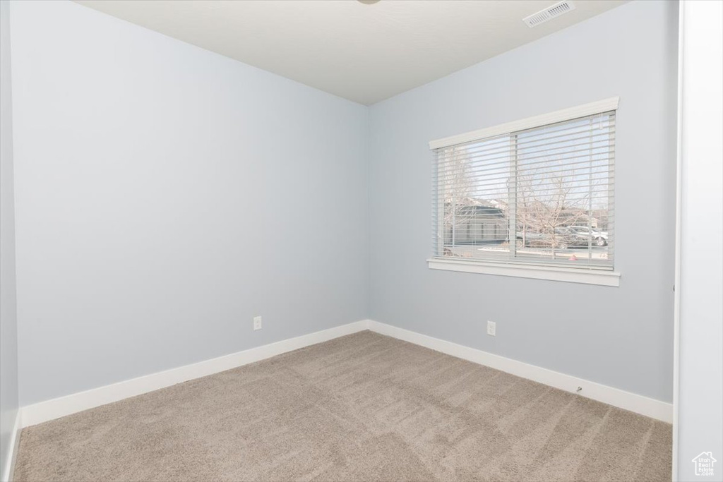 Empty room featuring visible vents, carpet floors, and baseboards