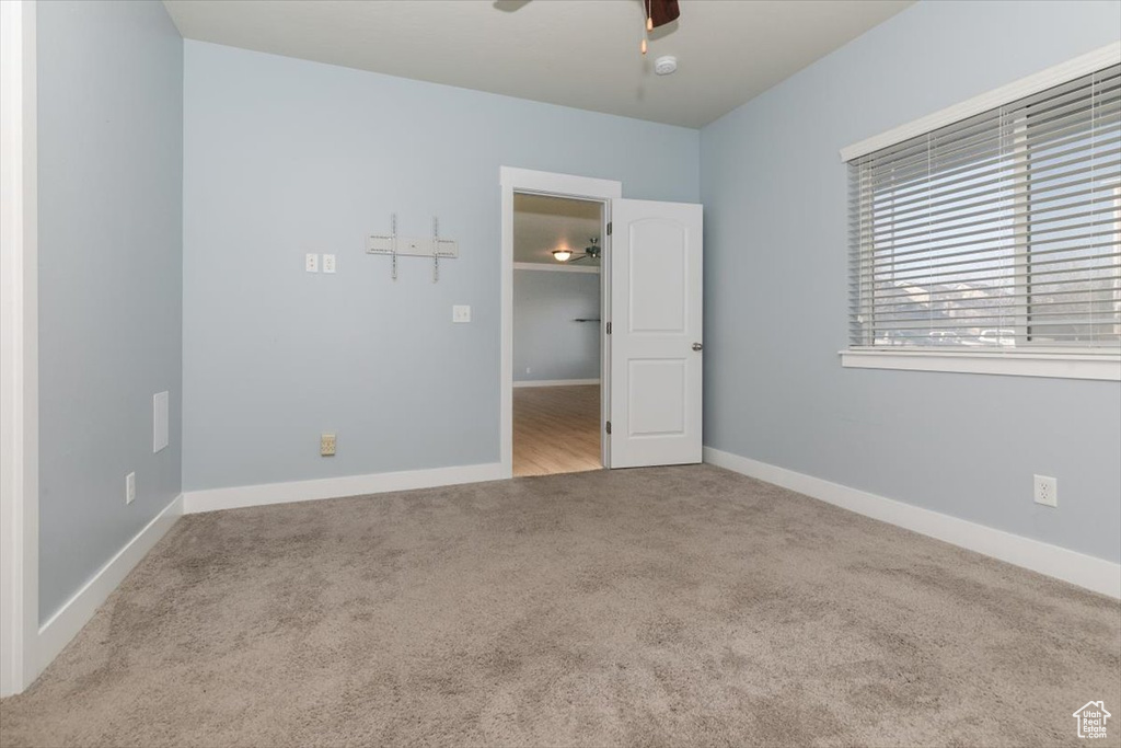 Carpeted empty room with a ceiling fan and baseboards