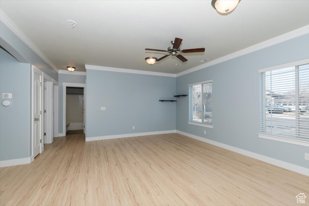 Spare room featuring crown molding, baseboards, light wood-type flooring, and ceiling fan