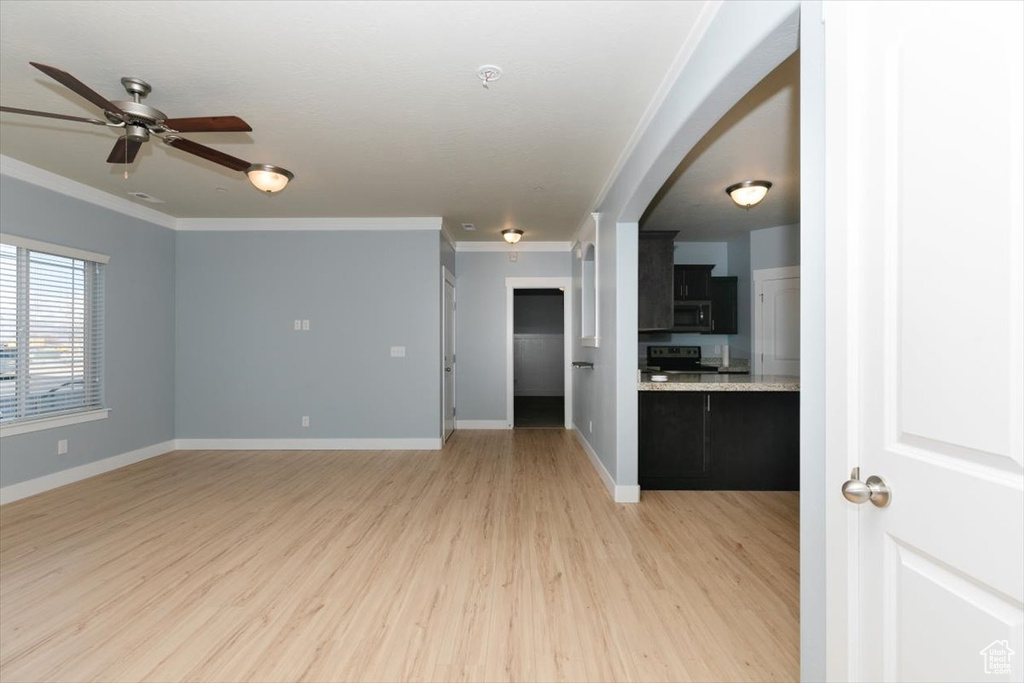 Unfurnished living room with ceiling fan, baseboards, light wood finished floors, and ornamental molding