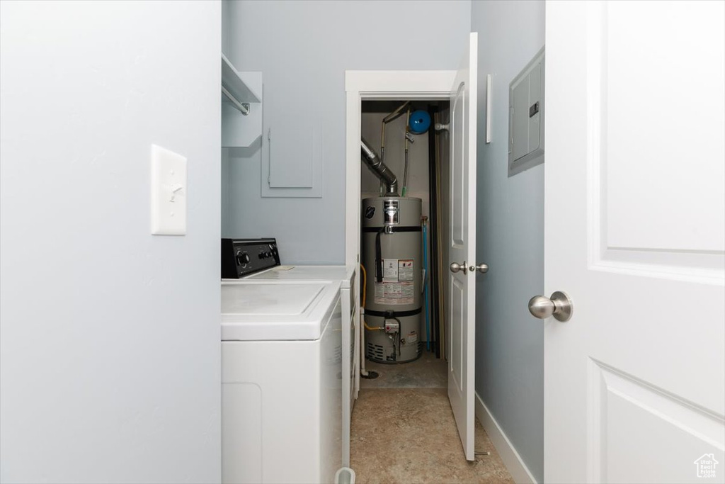 Laundry area featuring washing machine and clothes dryer, baseboards, strapped water heater, electric panel, and laundry area