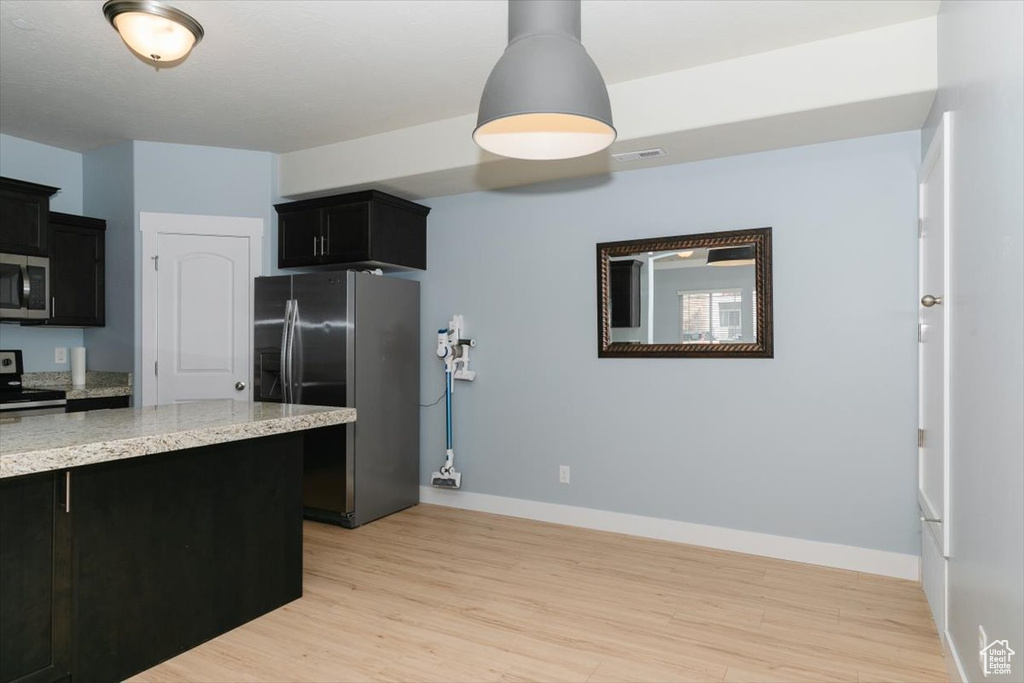 Kitchen with visible vents, stainless steel appliances, light wood-type flooring, and dark cabinets