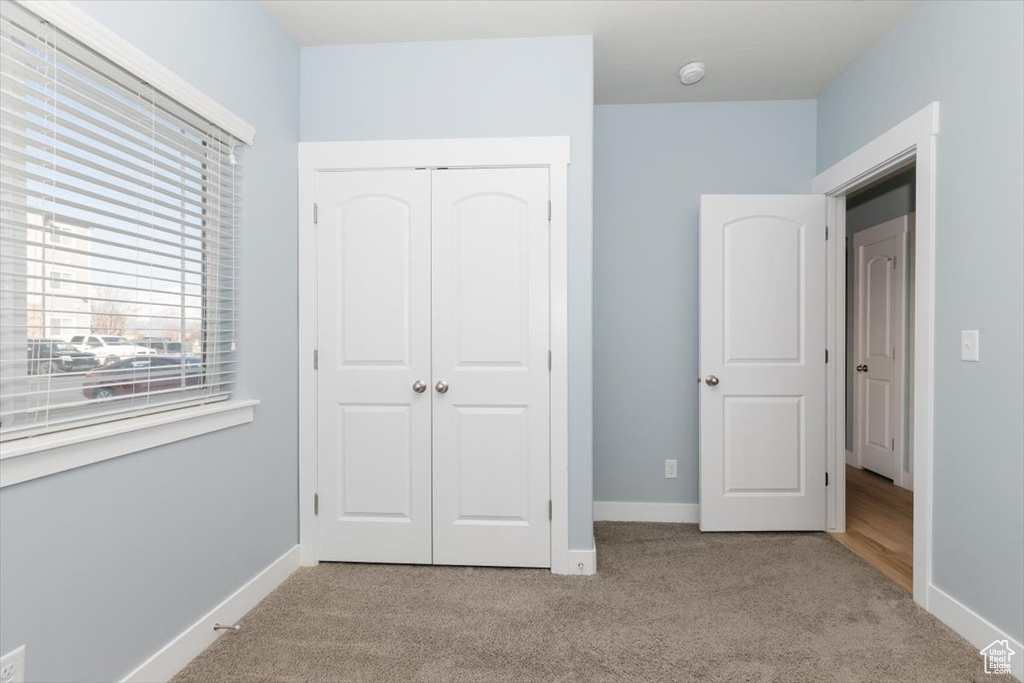 Unfurnished bedroom featuring a closet, carpet floors, and baseboards