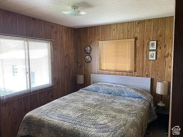 Bedroom featuring wooden walls and a textured ceiling