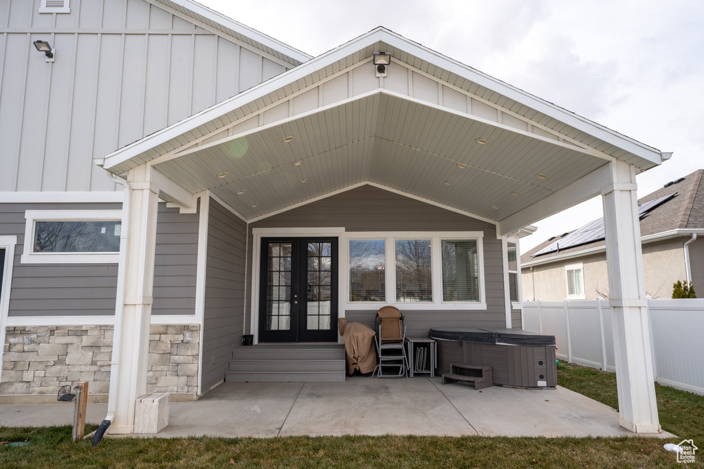 Back of property featuring a hot tub, a patio, fence, french doors, and board and batten siding