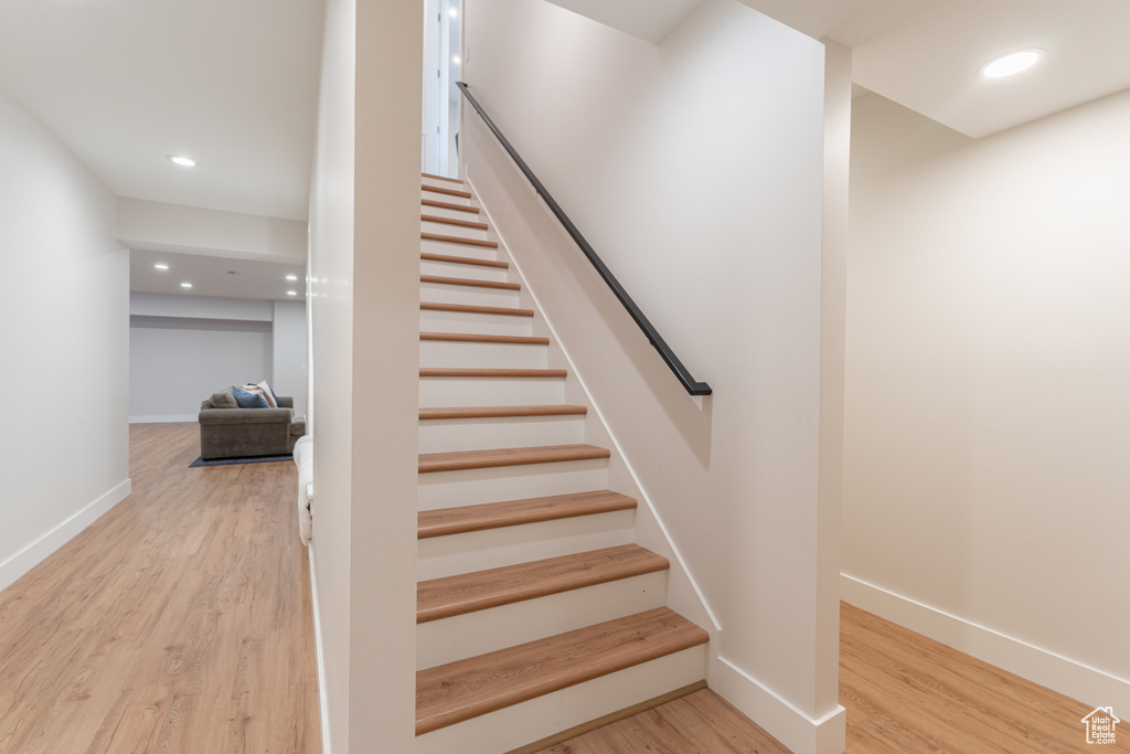 Staircase featuring baseboards, wood finished floors, and recessed lighting