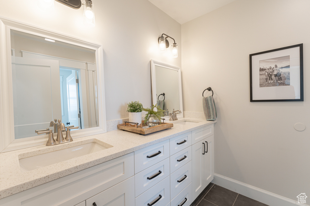 Bathroom with double vanity, tile patterned flooring, a sink, and baseboards