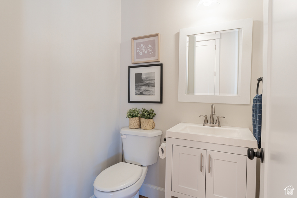 Half bathroom with toilet, baseboards, and vanity