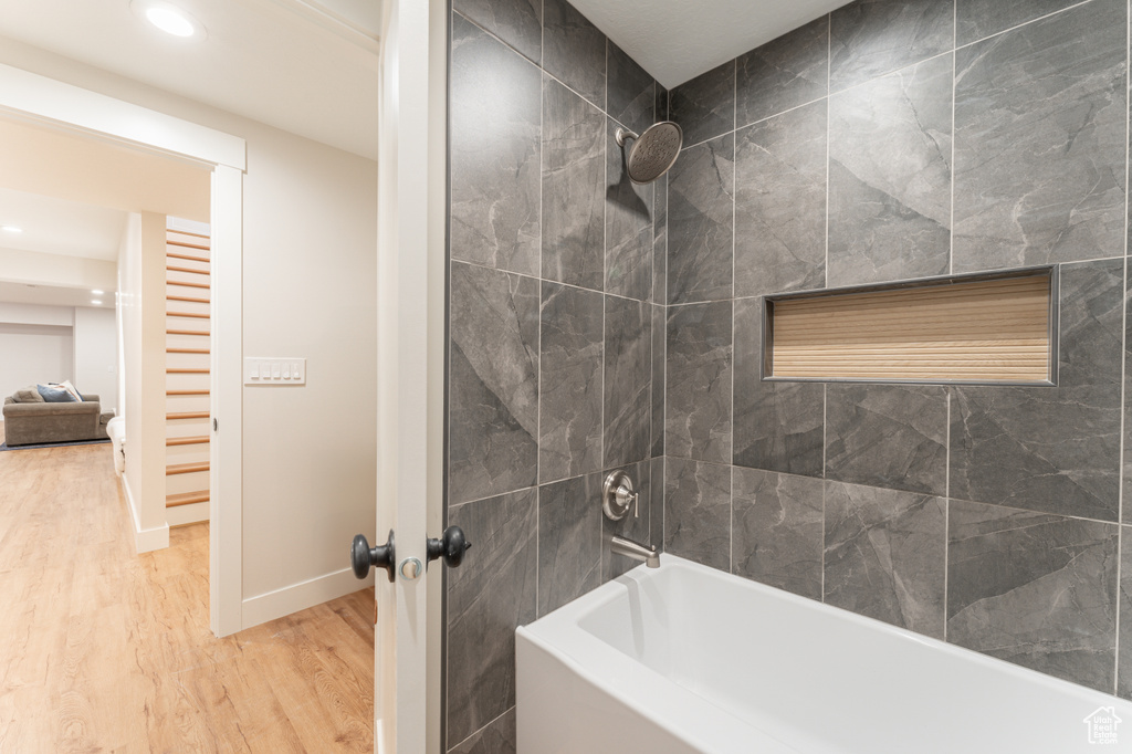 Bathroom with recessed lighting, shower / bathing tub combination, baseboards, and wood finished floors
