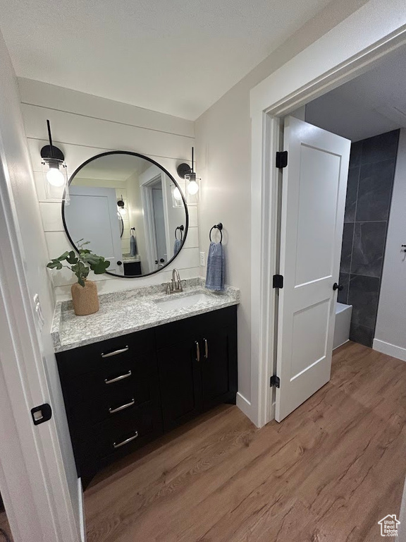 Bathroom with vanity, wood finished floors, and baseboards