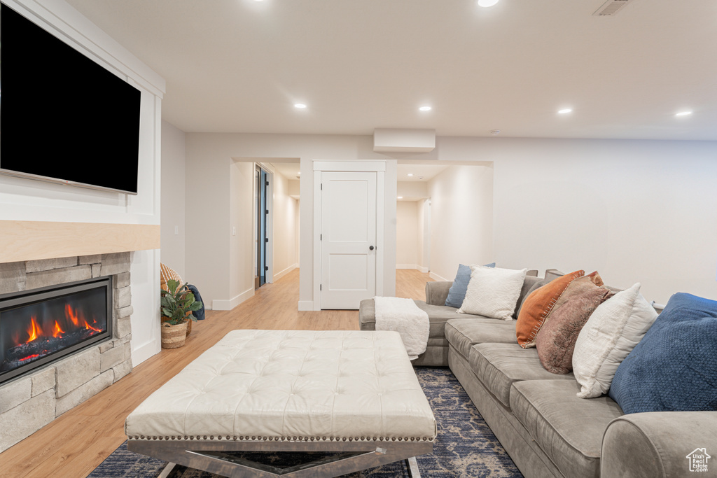 Living room with a fireplace, baseboards, wood finished floors, and recessed lighting