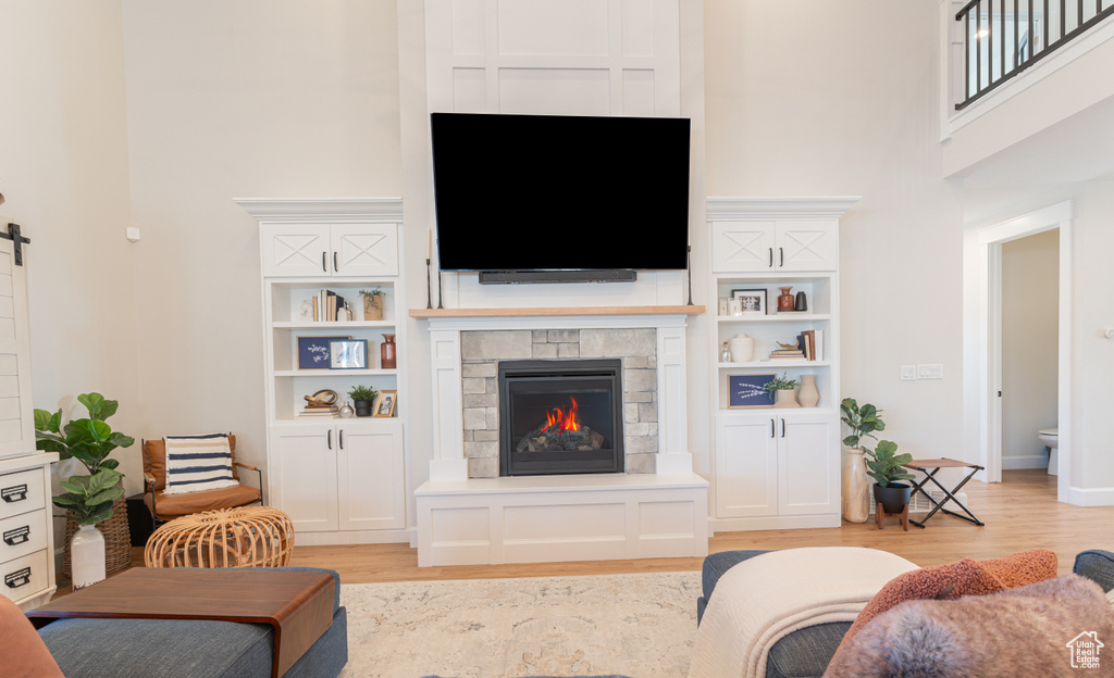 Living area with a barn door, a fireplace, light wood-style flooring, and a towering ceiling