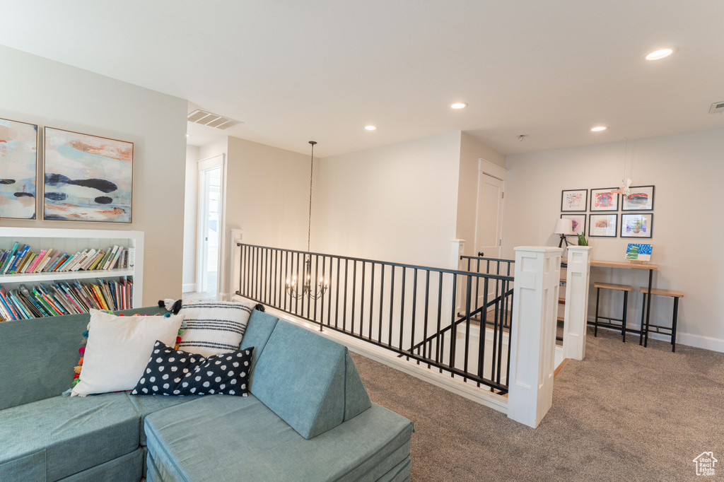 Living area featuring carpet floors, recessed lighting, visible vents, and an upstairs landing