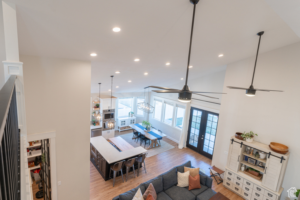 Living area featuring ceiling fan, light wood-style flooring, recessed lighting, vaulted ceiling, and french doors