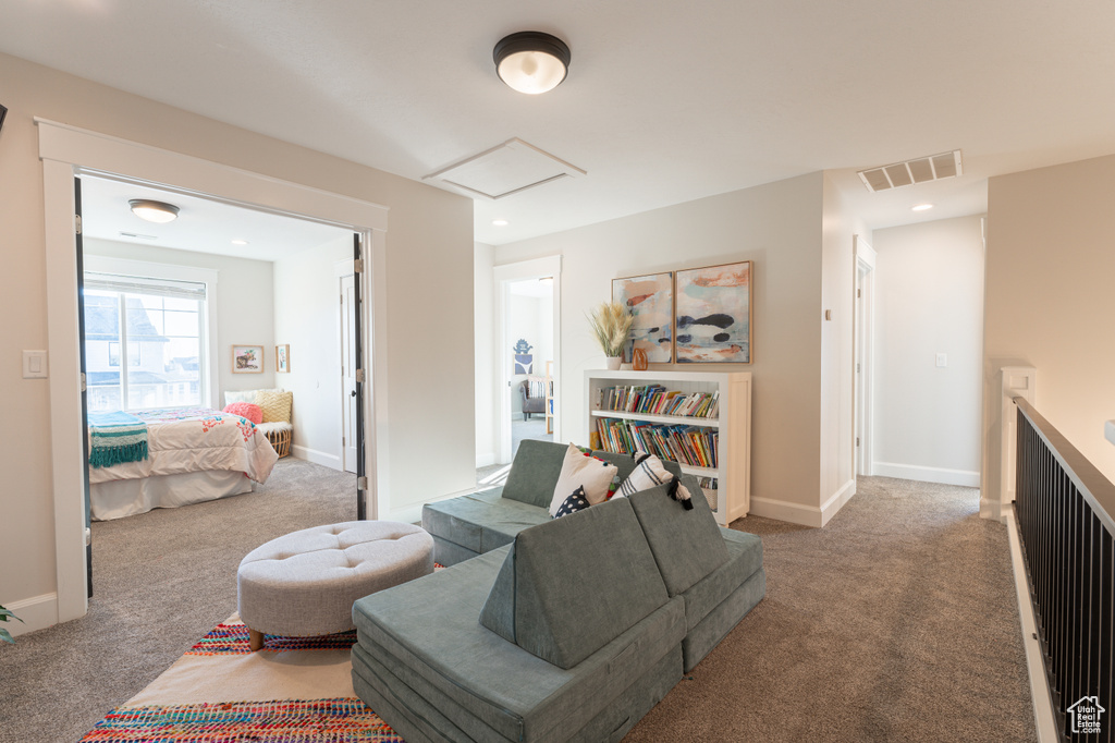 Carpeted living area with visible vents, recessed lighting, attic access, and baseboards