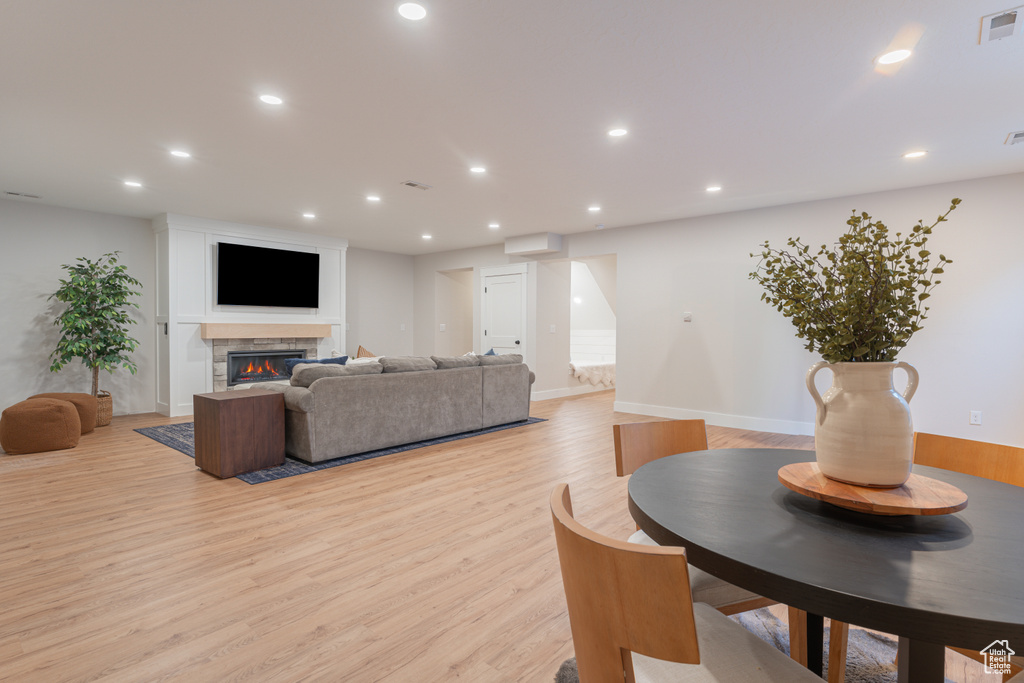 Living room with recessed lighting, light wood-style flooring, visible vents, and a glass covered fireplace
