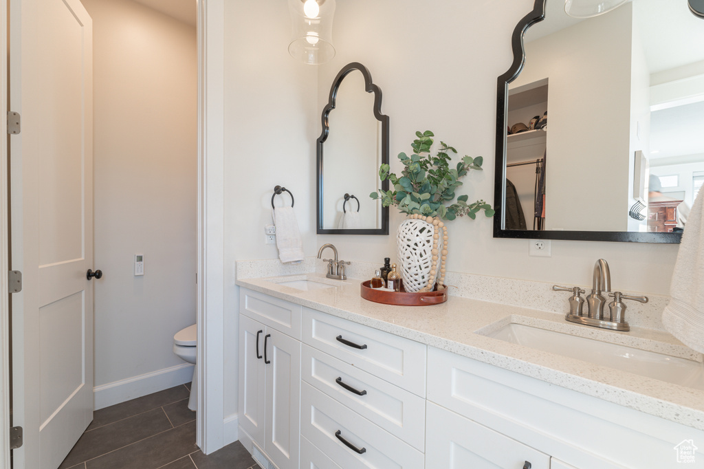 Full bath with toilet, tile patterned flooring, double vanity, and a sink