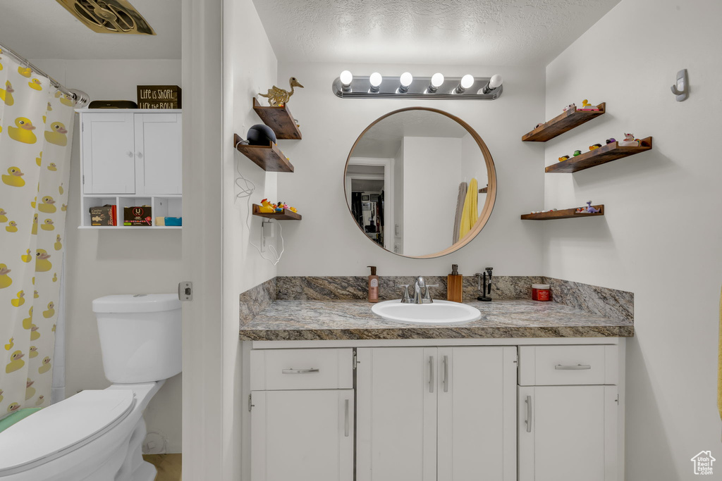 Full bath featuring vanity, toilet, and a textured ceiling