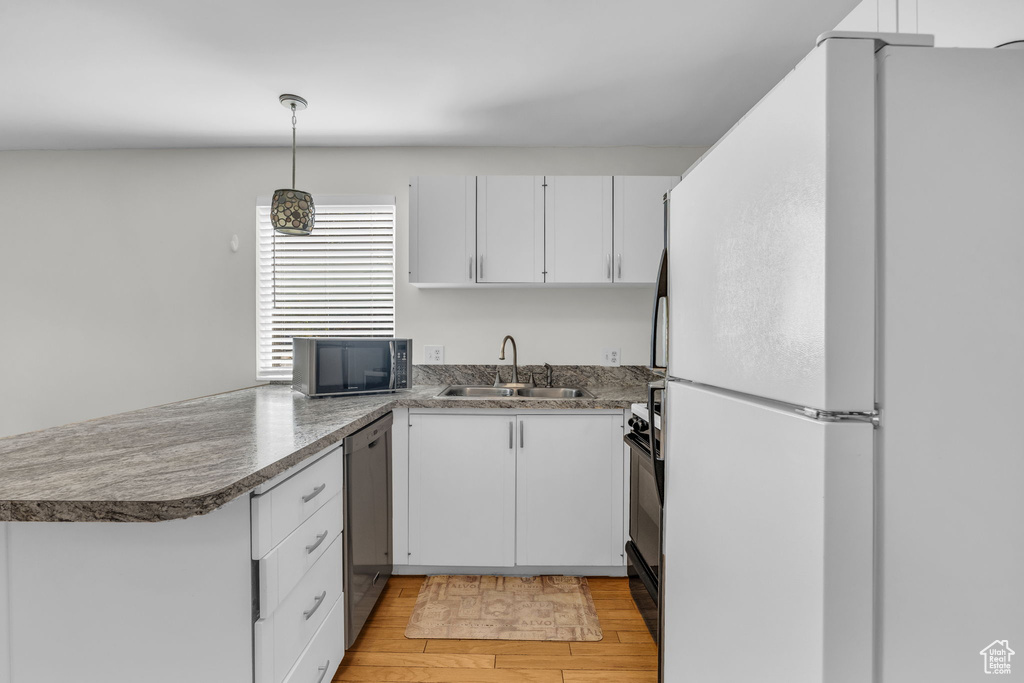 Kitchen featuring freestanding refrigerator, stainless steel dishwasher, white cabinetry, and a sink
